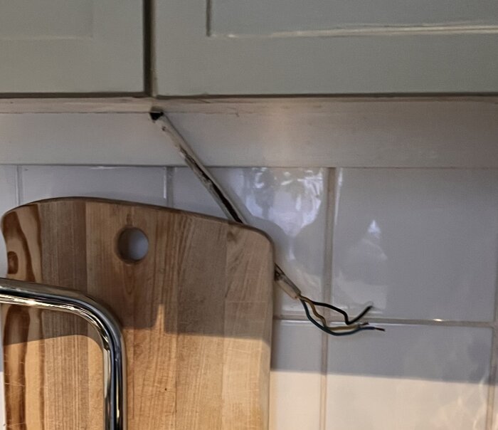 Lösa eltrådar hänger under köksskåp ovanför diskbänken efter borttagen lampa.