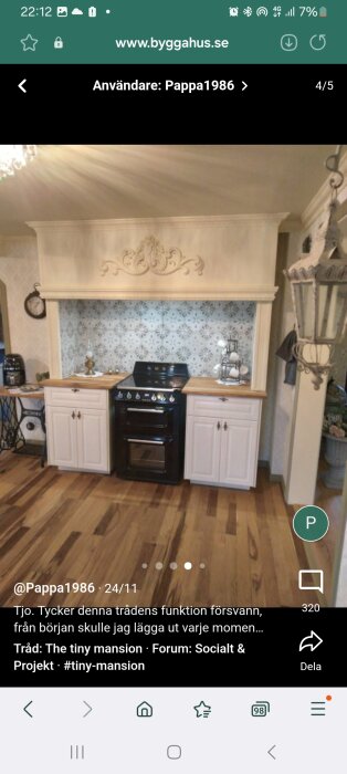 Handbyggd kökskåpa med dekorativ design ovanför en svart spis, omgiven av vita skåp och mönstrat kakel, med träbänkskivor.