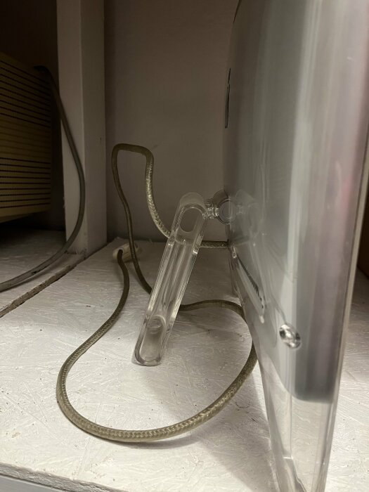Gammal Apple-skärm från cirka 2000, visar bakre stödben och kabel på en hylla. Fokus på behovet av att limma stödbenet.