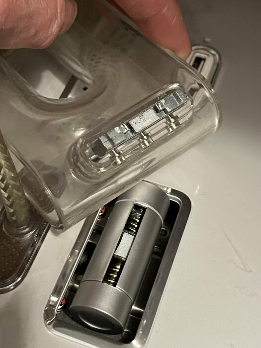 Närbild av en trasig plastdel och metallfäste på en gammal Apple-skärm från cirka 2000.