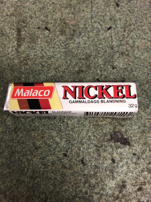 Förpackning av Malaco Nickel gammaldags blandning, 32g, liggande på grön yta.