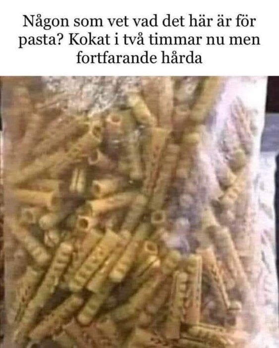 Påsen innehåller gula, spiralliknande pastabitar med många hål, liknande märlor eller byggdetaljer i plast.