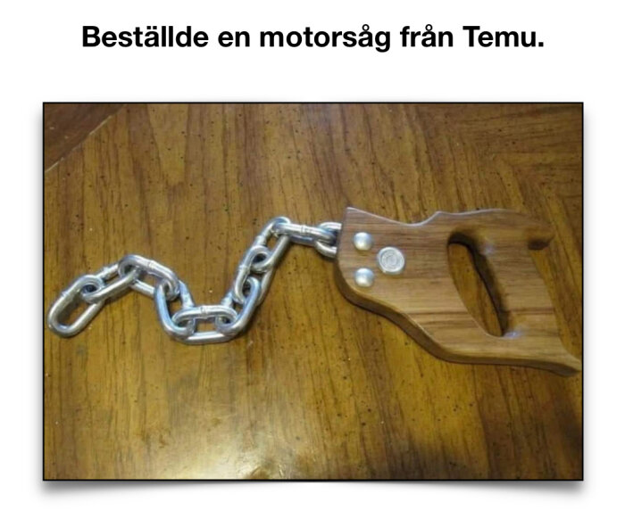 Träskaft med handtag och kedja, liknande en motorsåg, på ett träbord.