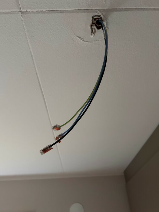 Lös elkabel hänger från taket med tre exponerade ledare och kopplingsklämmor.