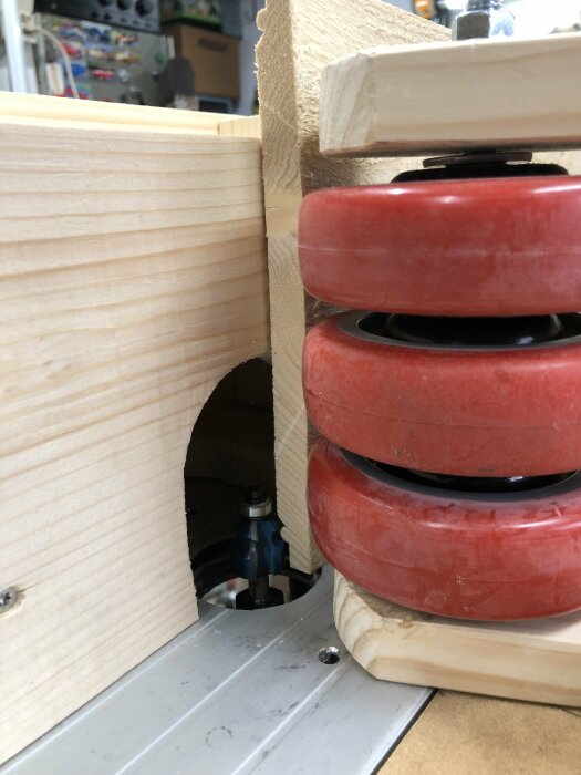 Närbild på en träbänk med röd hjulkonstruktion och utsnitt av en verktygsmaskin i garaget.