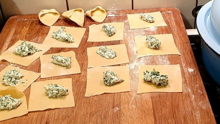 Hemgjord pasta med fyllning på en träskärbräda, fyllda pastabitar och några formade tortellini.