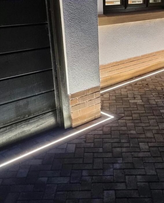 LED-strip nedfräst i marksten längs husvägg.