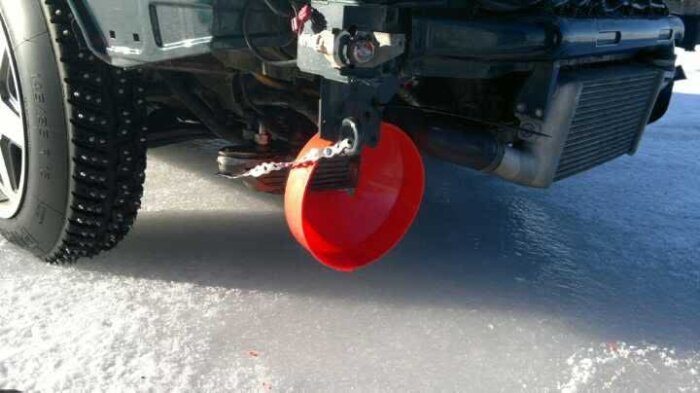 Bilden visar en bilfront med en röd tratt fastsatt som en improviserad lufttratt, parkera på is, för att styra luftflödet till motorns oljekylare.