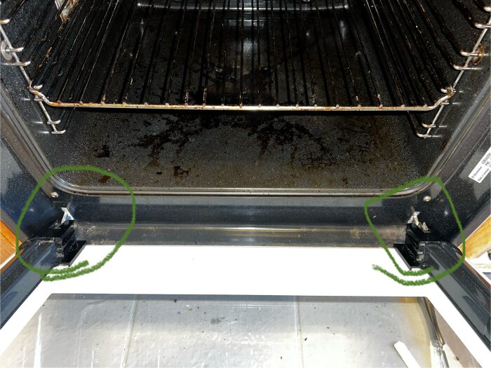 Ugn med öppen lucka, visar klämspakar på sidorna; den vänstra avhakad, den högra fastnar. Grönt markerar problemområdet.