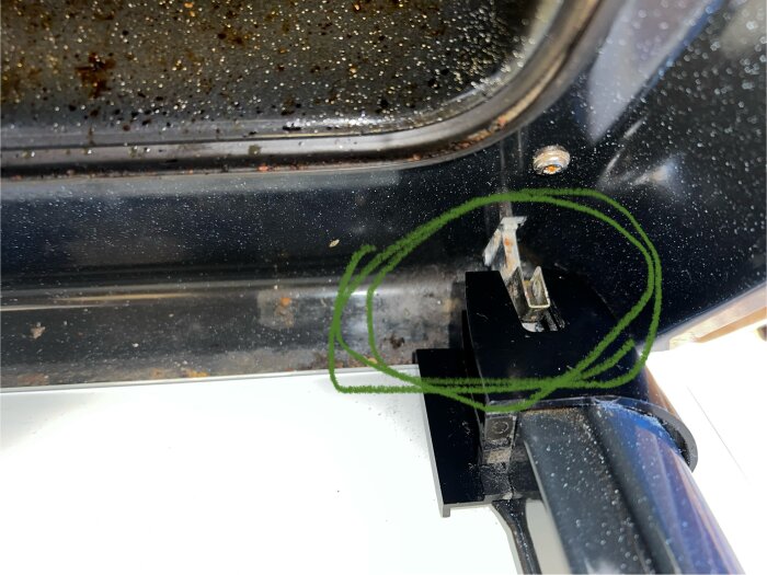 Ugnsluckans krok med avhakad klämspak på Electrolux-ugn, visar problem med stängningens mekanism.