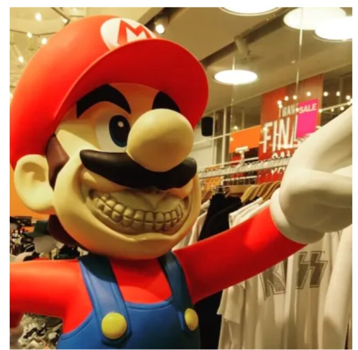 En stor staty av en känd, leende spelkaraktär med röd keps och blå overaller står inuti en klädbutik.