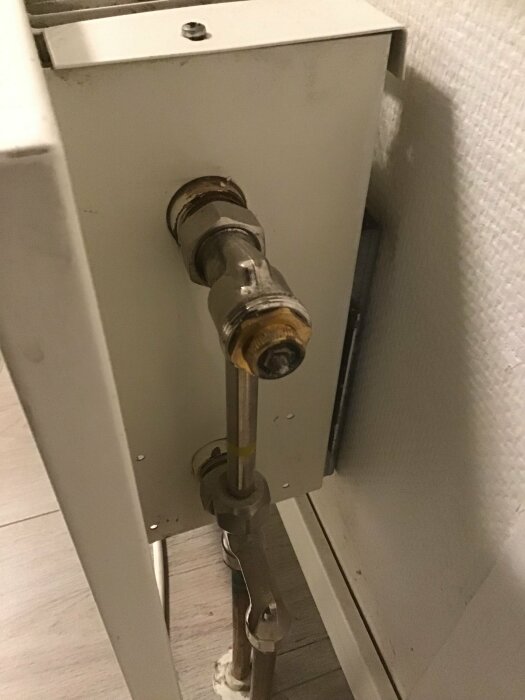 Radiatorventil kopplad till ett rör i ett hem, med fokus på delen där ventilen är ansluten till elementet.