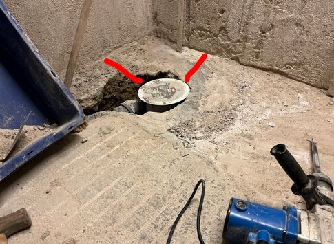 Golvläggning med synlig golvbrunn nära hörnet i byggplats. Verktyg och rördelar finns i närheten.