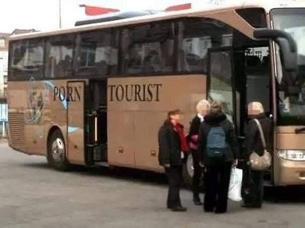 En buss med texten "PORN TOURIST" och några människor som står bredvid den.