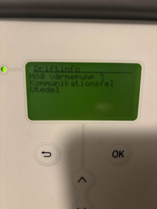 Display på värmepump visar "Hög värmepump" och "Kommunikationsfel Utedel", med en grön bakgrund och knappar för navigering.