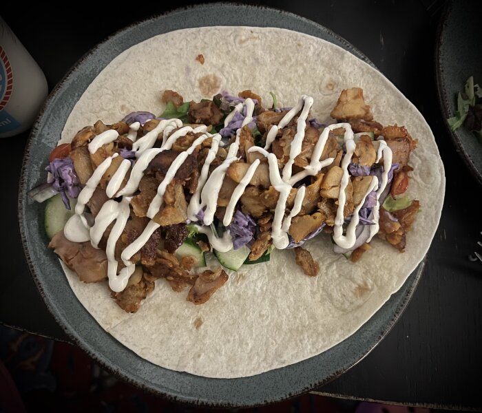 Kycklingkebab i en mjuk tortilla med sallad, gurka, tomat, rödlök, inlagd chili, rödkål och kebabsås.