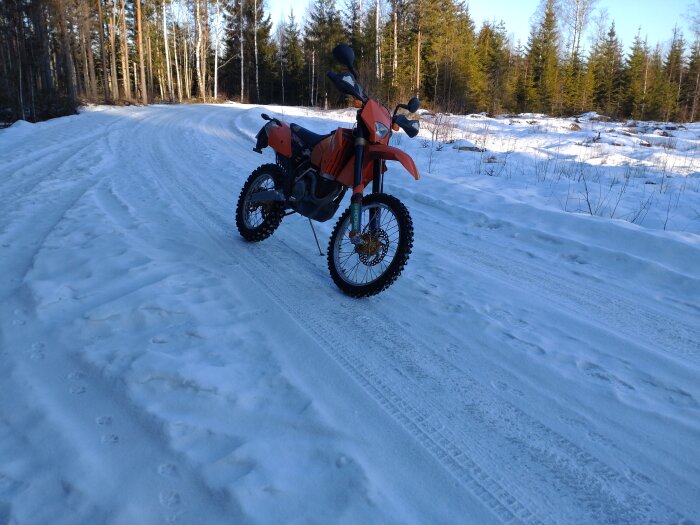 Motorcykel med dubbade däck på en snöig skogsväg under en provtur.