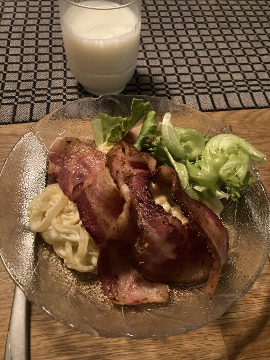 Stekt fläsk med löksås och sallad på en tallrik, serverat med ett glas mjölk på bord med rutigt mönster.