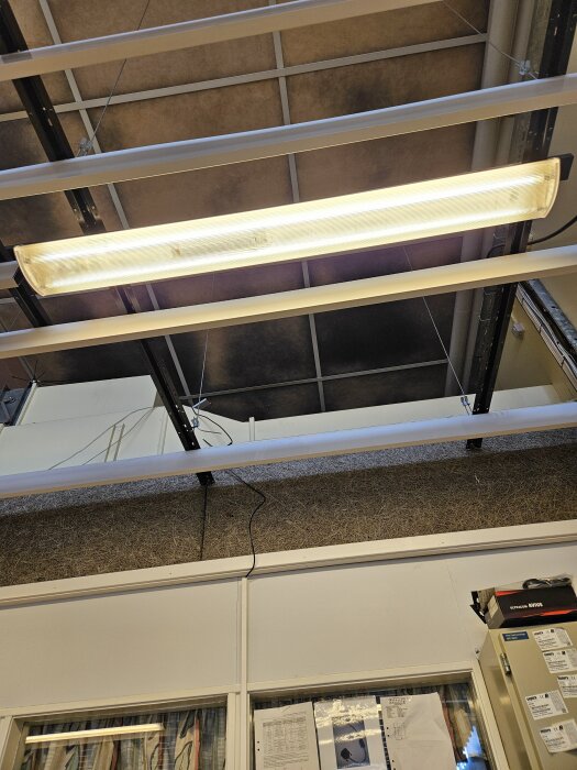 Innertak med mörka fläckar och lysrörsarmatur, potentiellt sot eller mögelproblem.