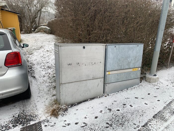 Bil parkerad bredvid elskåp på smal, snöig uppfart.