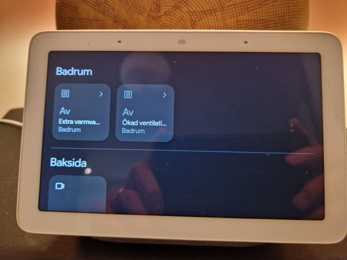 Google Nest Hub visar inställningar för badrum, inklusive extra varmvatten och ökad ventilation, på en svart skärm.