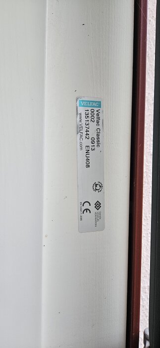 Etikett på Velfac-fönster, visar modell och certifieringar, relaterar till diskussion om gasläckageproblem i fönstren installerade 2013.