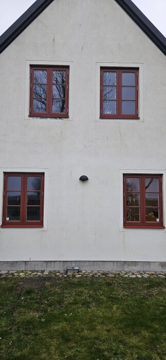Fasad med fyra träfönster från Velfac. Två på varje våning av ett vitputsat hus, möjligen med kondensfläckar mellan rutorna.