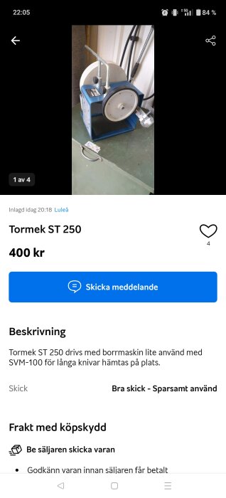 Slipmaskin Tormek ST 250 med blå ram och vit slipskiva står på ett grönt bord, omgiven av borrmaskinstillbehör.