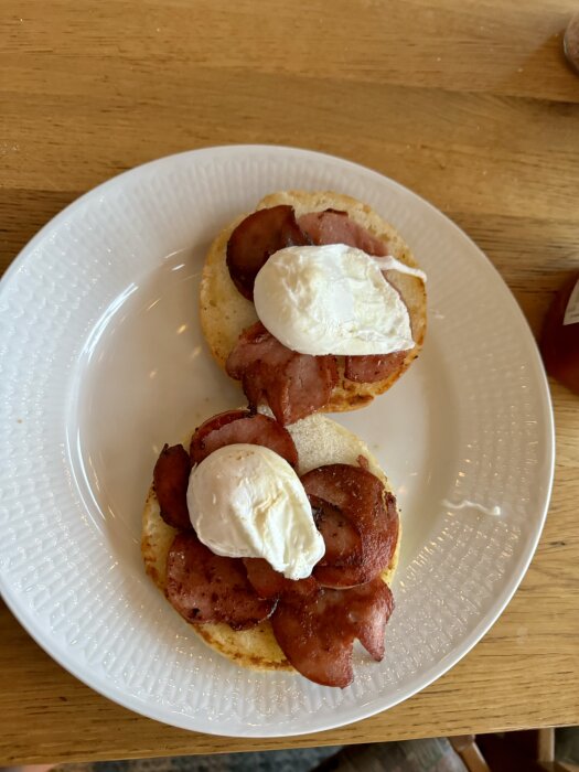 Två smörgåsar på vit tallrik med stekt korv och pocherat ägg.