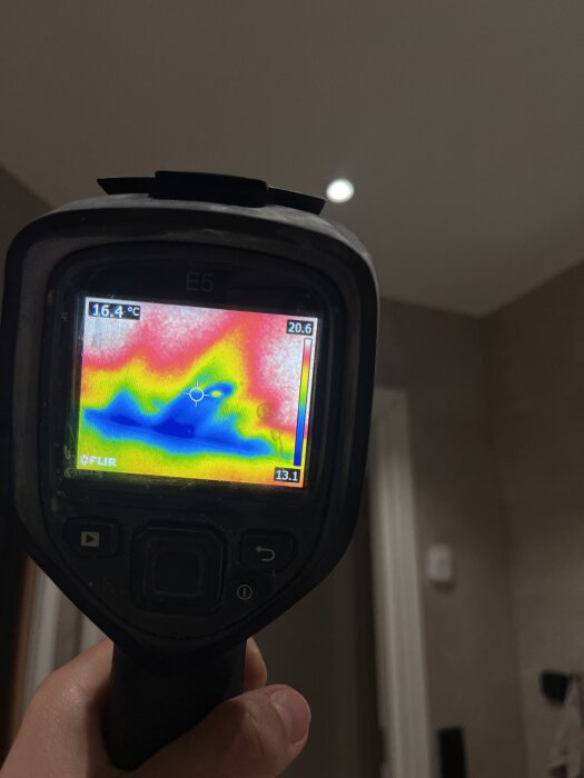 Termografikamera visar färgskala för temperaturskillnader i ett badrum, med områden i blått, grönt och rött.