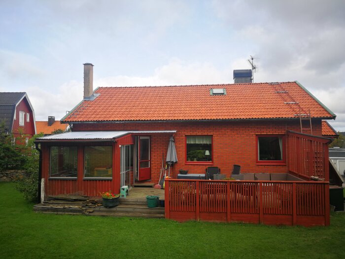 Rött tegelhus med rött tak och detaljer. Röd veranda framför huset.