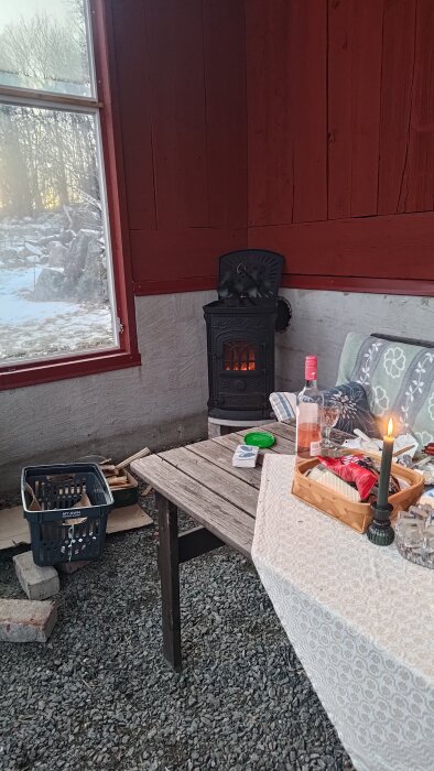 Eldstad i växthus med vinflaska, ost och ett tända ljus på ett träbord.