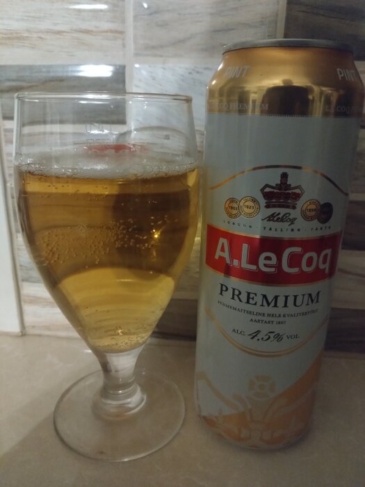 A. Le Coq Premium ölburk och ett glas öl på ett bord.