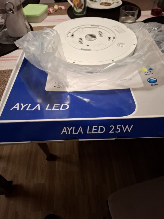 Ayla LED 25W lampa och förpackning på ett bord, ämnad för badrumsinstallation.