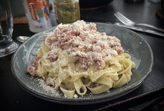 Krämig salsicciapasta med grädde och vitt vin serveras på en tallrik, toppad med riven parmesanost.