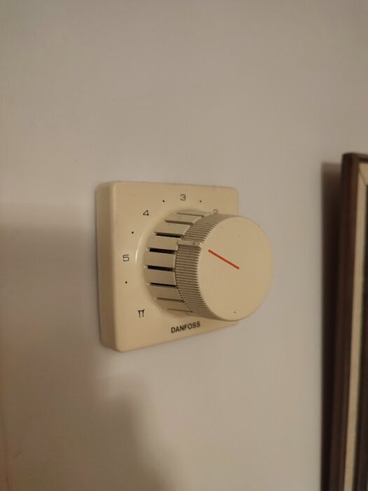Termostat från Danfoss på en vägg, inställd på nivå 5.
