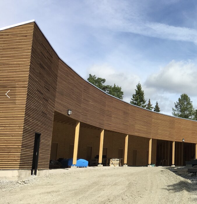 Garage med grånat, obehandlat trä från byggåret 2015, omgivningen inkluderar himmel och träd.