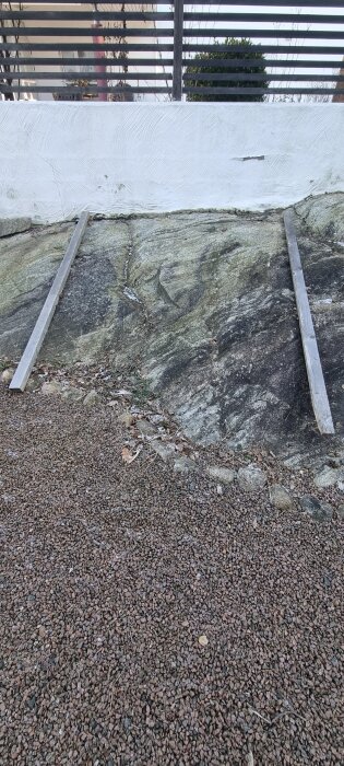 Två brädor placerade på ojämn berggrund för att illustrera plan för rektangulär odlingslåda.