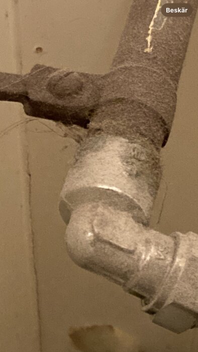 Närbild av ett dammigt rör med en skarv som har en lindning mellan delar av röret, potentiellt från en gammal renovering.