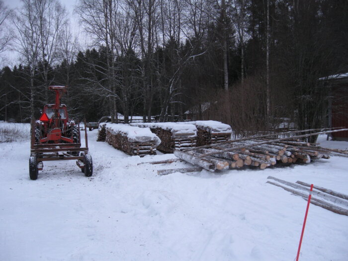 Traktor och vedstaplar i vinterskogsmiljö för vedproduktion.