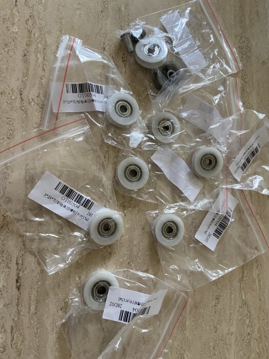 På bilden syns flera vita hjul eller rullar i plastpåsar med streckkoder, placerade på en bordsyta.