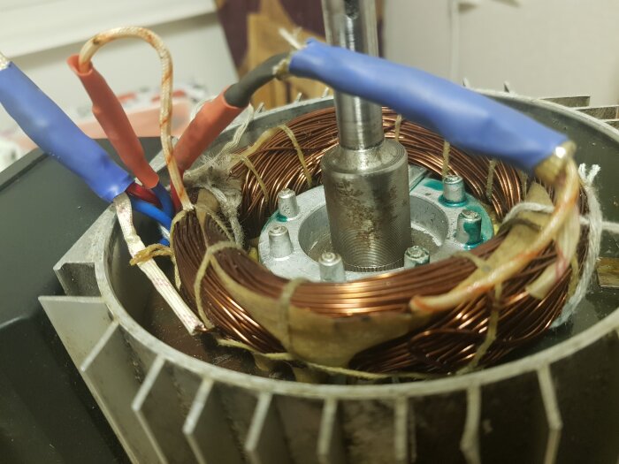Närbild av insidan på en elmotor med synliga koppartrådar, kablar och metallkomponenter.