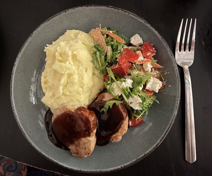 Fläskfilé med rödvinssås, hemgjort potatismos och sallad på en tallrik.