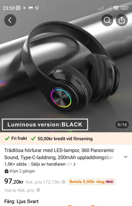 Svarta trådlösa hörlurar med LED-lampor och 360 ljud, liggande på grå yta.