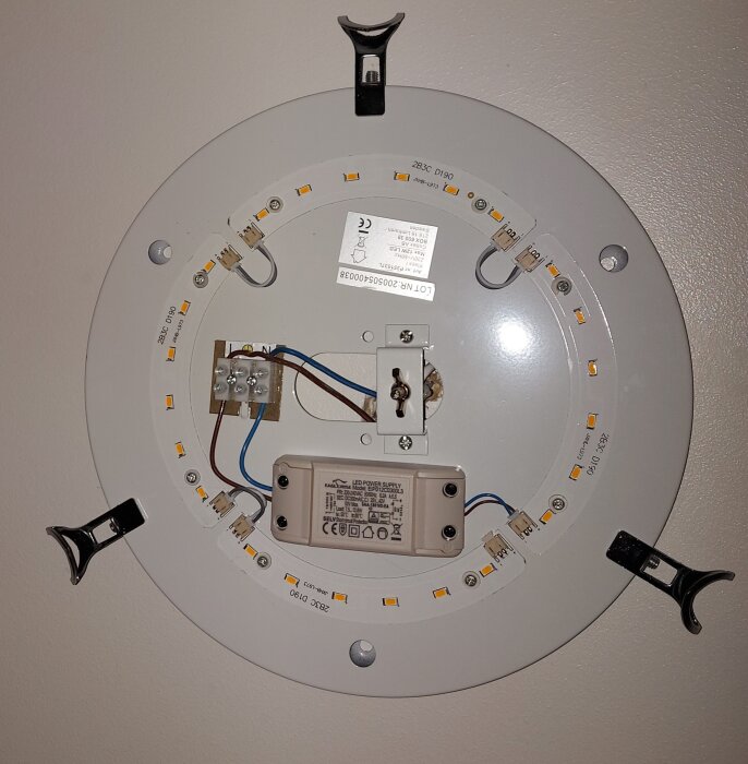 LED-ljusplatta med anslutna kablar och komponenter monterad på en cirkulär metallplatta.