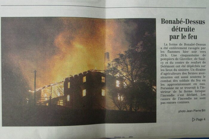 Ett hus står i lågor under natten, med kraftiga flammor som kastar ett orange sken över byggnaden.