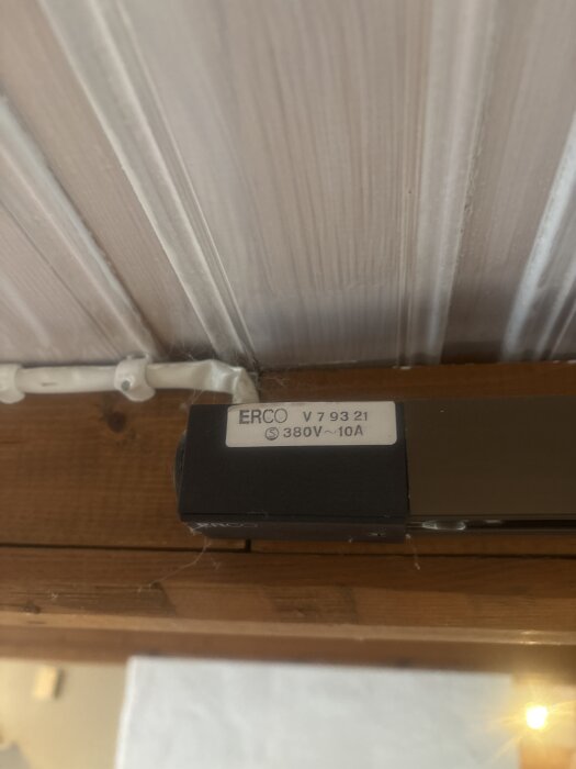 ERCO belysningsskena i tak, märkt 380V 10A, med smalt utseende och en strömbrytare. Möjlighet att koppla till tre faser syns på bilden.