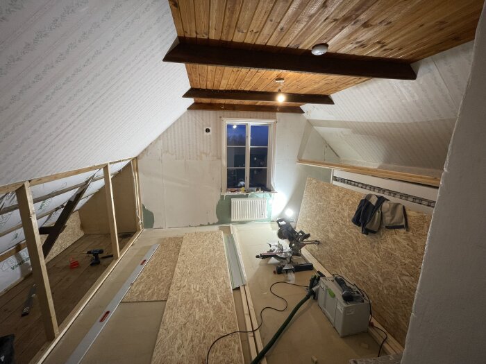 Renovering av sovrum med öppen kattvind, synliga takstolar och en kap- och geringssåg på golvet.