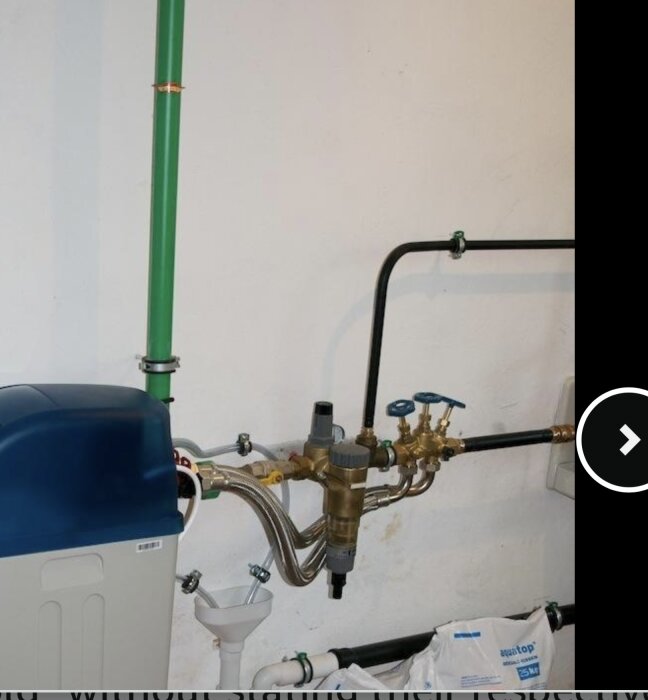 Bild av en installation med grönt rör och kopparventiler kopplade till en blå enhet mot en vit vägg, med olika anslutningar och påsar nedanför.