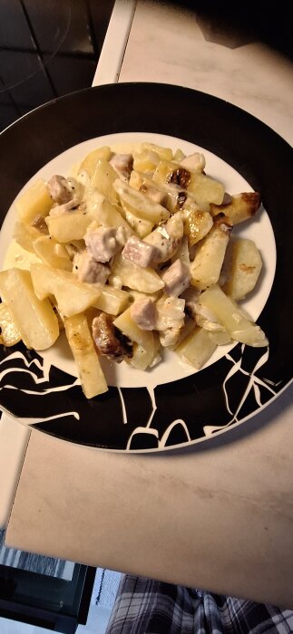 Tallrik med potatisgratäng och kassler på ett bord.